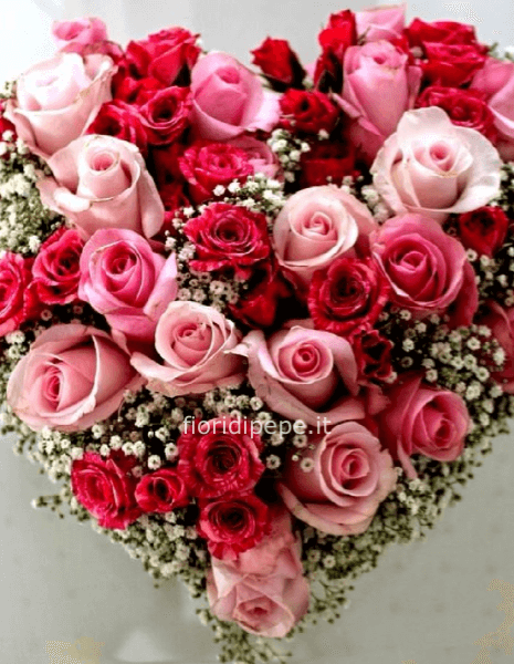 Composizione a forma di cuore con rose di colori assortiti.